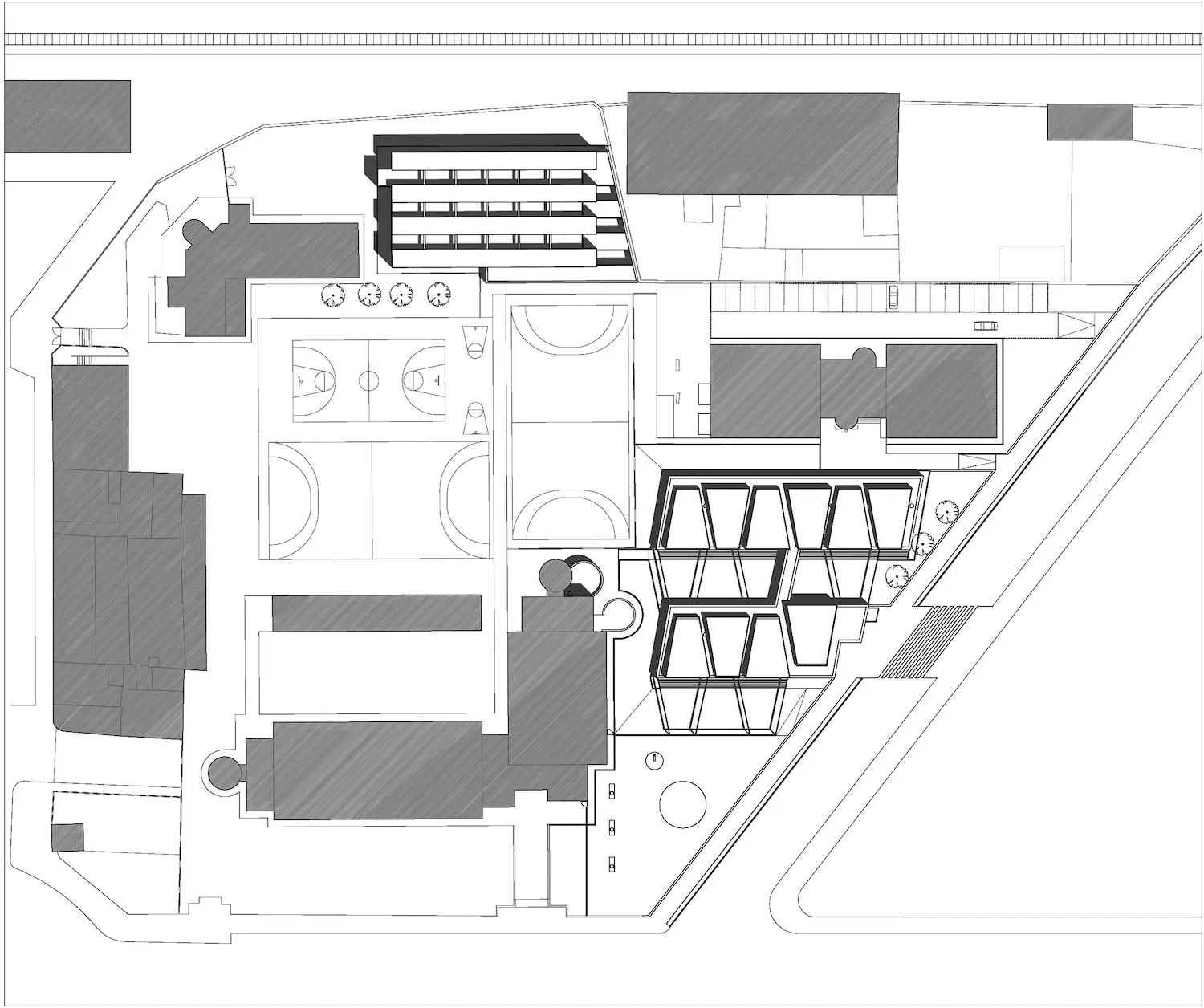 Plano arquitectónico en blanco y negro que muestra múltiples edificios rectangulares, canchas de baloncesto al aire libre, zonas de aparcamiento, pasarelas y espacios ajardinados dentro de una manzana definida a lo largo de carreteras que se cruzan.