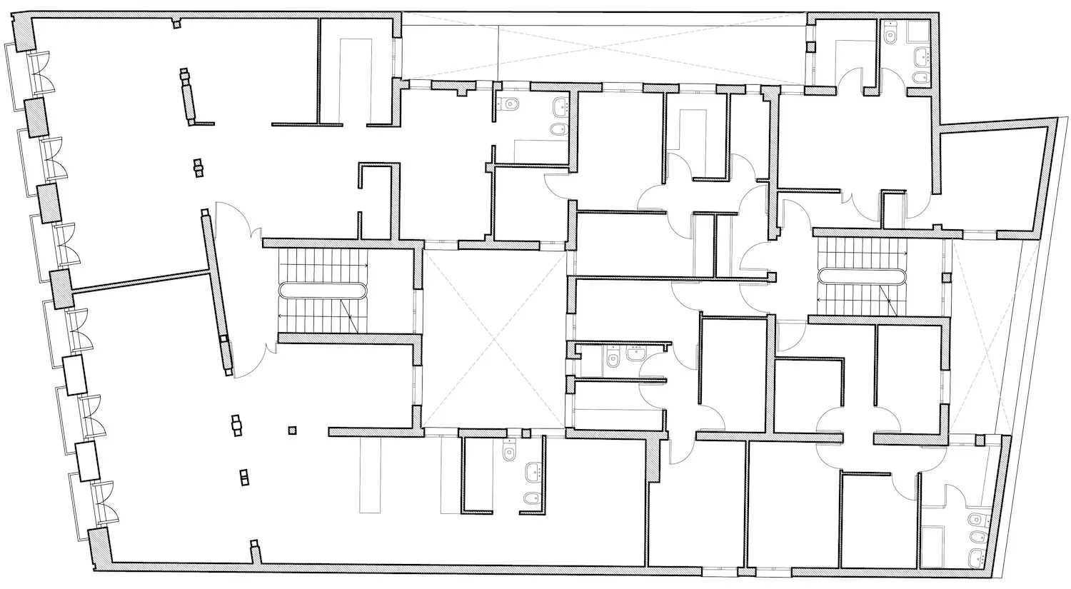 Plano arquitectónico en blanco y negro de un edificio que muestra una distribución con múltiples habitaciones, pasillos, escaleras y baños. El diseño incluye habitaciones grandes y pequeñas con puertas y ventanas.